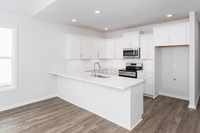 kitchen with white cabinetry, sink, stainless steel appliances, and kitchen peninsula