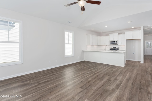 unfurnished living room with vaulted ceiling, dark hardwood / wood-style floors, sink, and ceiling fan