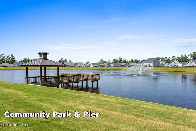 view of dock with a gazebo, a lawn, and a water view