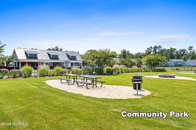 view of property's community with an outdoor fire pit and a lawn