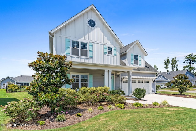 view of front of home with covered porch, a front yard, and a garage