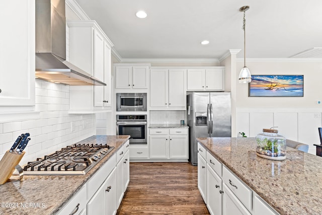 kitchen featuring appliances with stainless steel finishes, white cabinetry, wall chimney exhaust hood, pendant lighting, and dark wood-type flooring