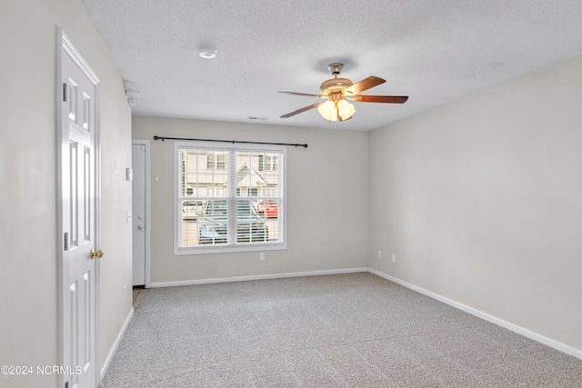 spare room featuring light colored carpet, ceiling fan, and a textured ceiling