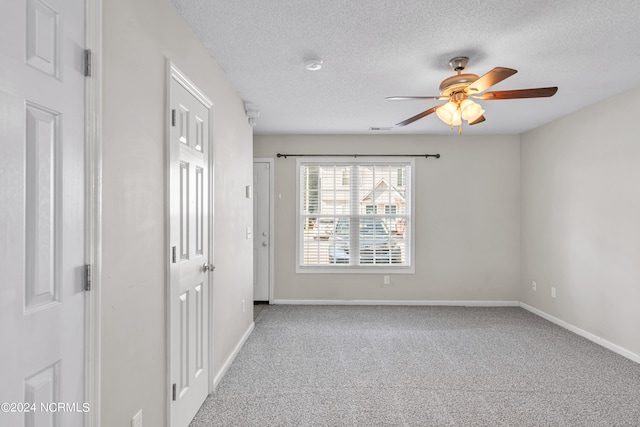 carpeted spare room with a textured ceiling and ceiling fan