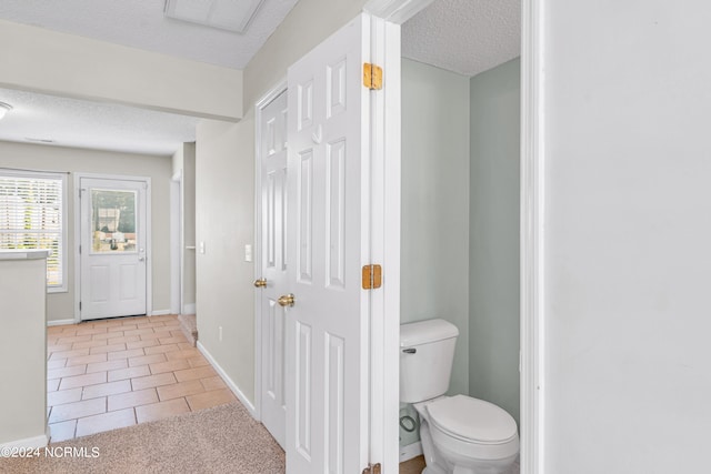 bathroom featuring tile patterned flooring, toilet, and a textured ceiling