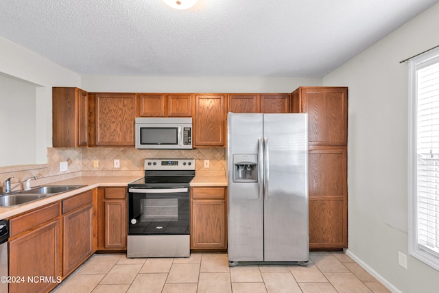 kitchen with a wealth of natural light, stainless steel appliances, decorative backsplash, and sink