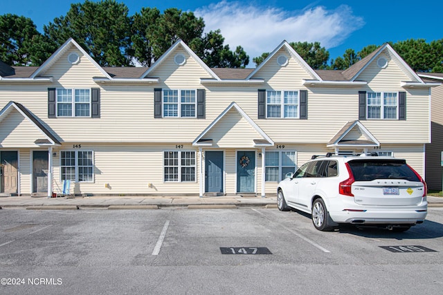 multi unit property featuring uncovered parking and a shingled roof