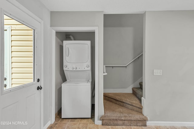 laundry room with light tile patterned floors, a textured ceiling, and stacked washer / drying machine