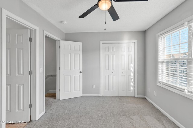 unfurnished bedroom featuring baseboards, ceiling fan, carpet, a textured ceiling, and a closet
