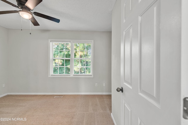 carpeted spare room featuring a textured ceiling and ceiling fan