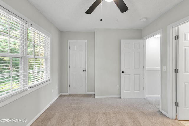 unfurnished bedroom featuring a textured ceiling, carpet, a ceiling fan, and baseboards