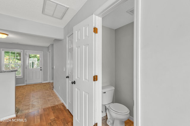 bathroom featuring visible vents, wood finished floors, toilet, and baseboards