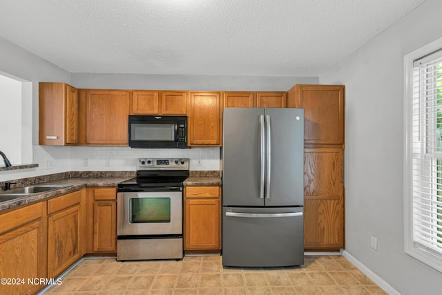 kitchen featuring appliances with stainless steel finishes, brown cabinetry, and a sink