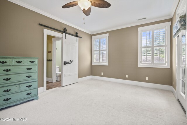 bedroom featuring light carpet, crown molding, a barn door, and connected bathroom