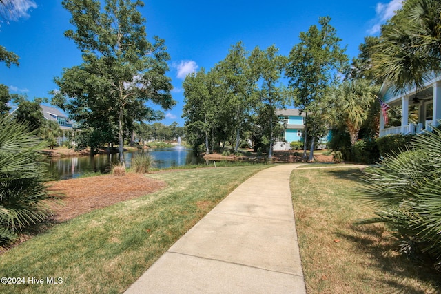 view of home's community with a water view and a lawn