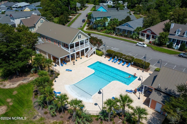 pool featuring a patio area, a sunroom, a residential view, and fence