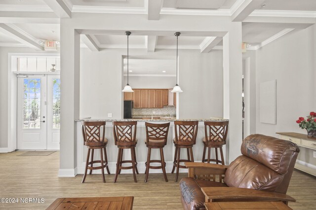 kitchen featuring black fridge, kitchen peninsula, backsplash, decorative light fixtures, and light wood-type flooring