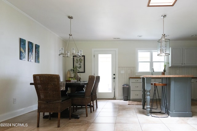 dining room featuring light tile patterned flooring, sink, crown molding, and an inviting chandelier