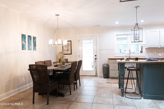 dining area featuring light tile patterned flooring, a healthy amount of sunlight, and a notable chandelier