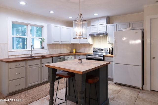 kitchen featuring sink, wooden counters, decorative light fixtures, a kitchen island, and appliances with stainless steel finishes