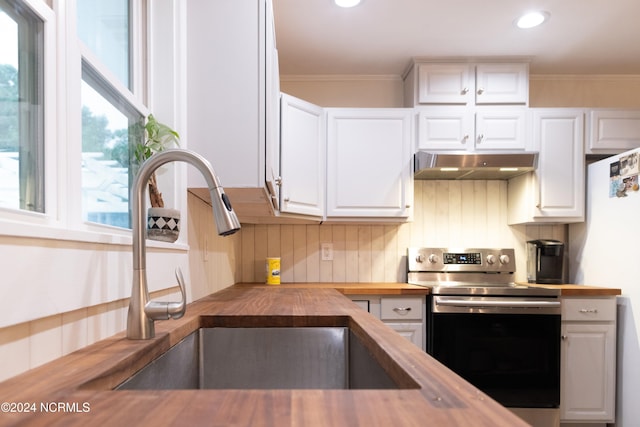 kitchen with stainless steel electric stove, butcher block counters, sink, and white cabinets