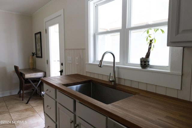 kitchen featuring gray cabinetry, crown molding, butcher block counters, and sink