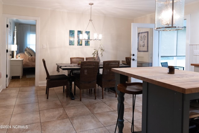 tiled dining area with a chandelier, plenty of natural light, and ornamental molding