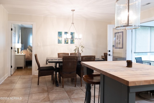 dining room featuring plenty of natural light, light tile patterned floors, ornamental molding, and a notable chandelier