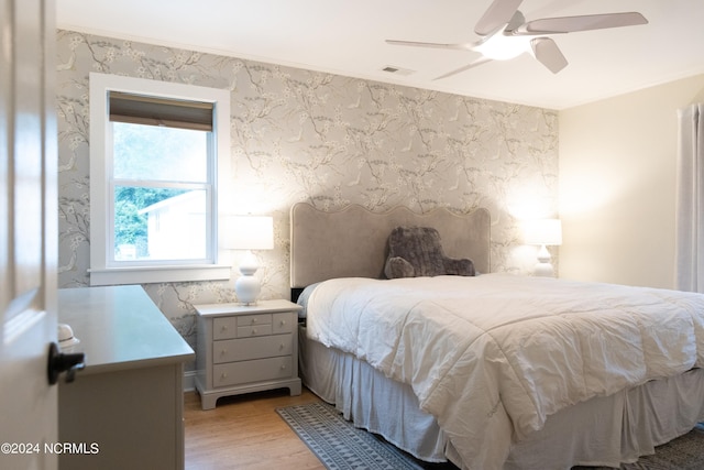 bedroom with light wood-type flooring, ceiling fan, and ornamental molding