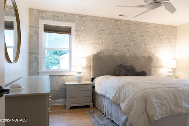 bedroom with ceiling fan, ornamental molding, and light wood-type flooring