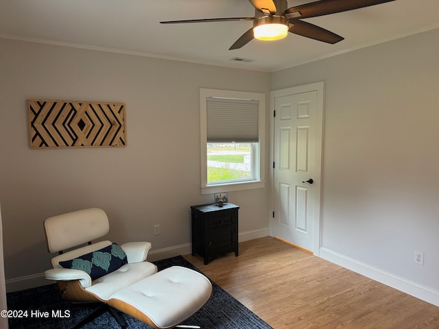 living area featuring ceiling fan, crown molding, and light hardwood / wood-style flooring