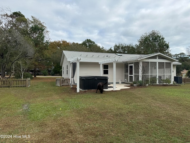 back of house with a sunroom, a yard, central AC, a patio area, and a hot tub