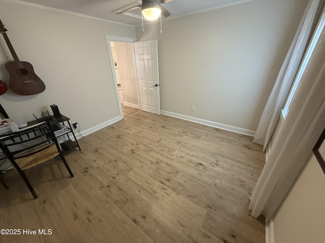 interior space featuring light wood-style flooring, baseboards, ceiling fan, and crown molding