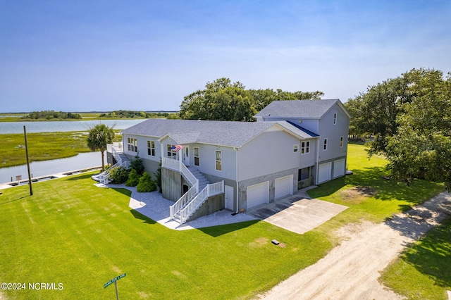 view of front of property with a garage, a front lawn, and a water view