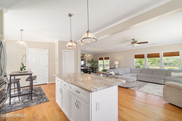 kitchen with white cabinetry, light stone counters, light wood-type flooring, and decorative light fixtures