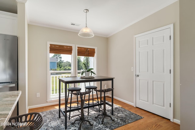 dining space with ornamental molding and light wood-type flooring