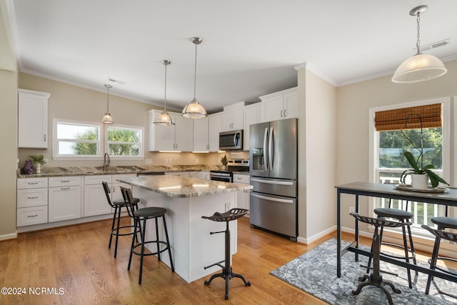 kitchen featuring appliances with stainless steel finishes, decorative light fixtures, a kitchen island, and white cabinets