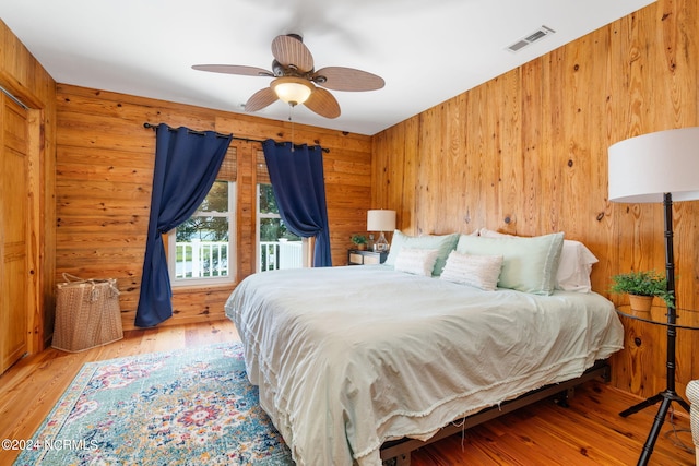 bedroom featuring wood-type flooring, ceiling fan, and wooden walls