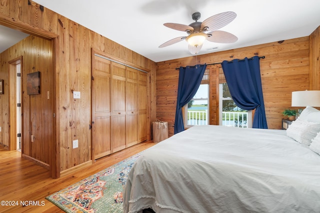 bedroom with a closet, wooden walls, ceiling fan, and hardwood / wood-style flooring