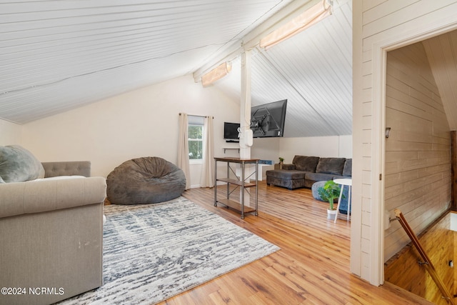 living room featuring wood walls, lofted ceiling with beams, and hardwood / wood-style flooring