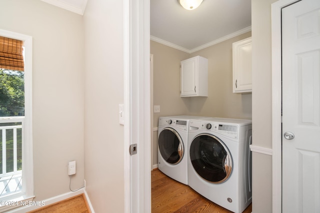 laundry area featuring light wood-type flooring, crown molding, washing machine and dryer, and cabinets