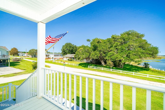 deck with a water view, a yard, and covered porch