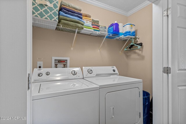 laundry room featuring laundry area, washing machine and dryer, ornamental molding, and a textured ceiling