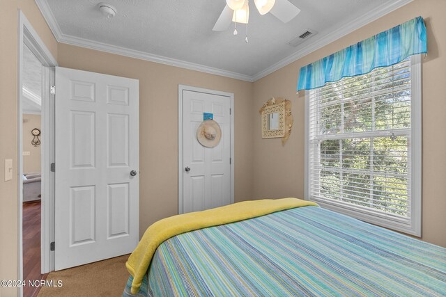 bedroom with carpet floors, visible vents, crown molding, and ceiling fan