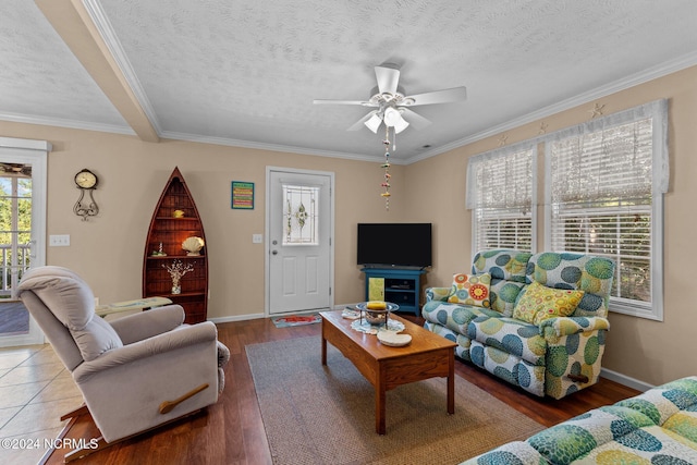 living area with a textured ceiling, ornamental molding, wood finished floors, and baseboards