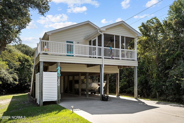 view of front facade with a carport, concrete driveway, ceiling fan, and a sunroom