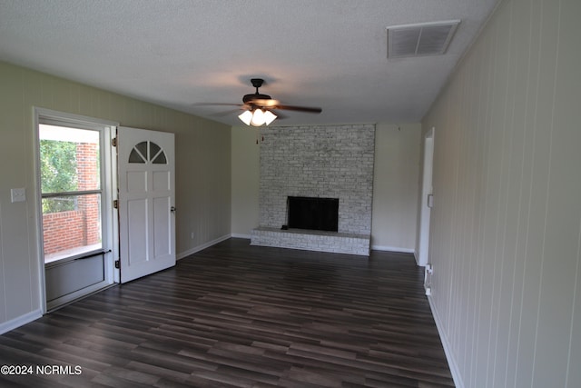 unfurnished living room with ceiling fan, a textured ceiling, dark hardwood / wood-style flooring, and a fireplace