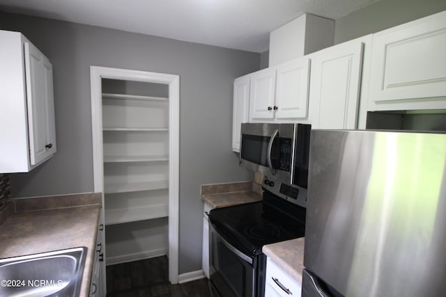 kitchen with white cabinets, appliances with stainless steel finishes, and dark wood-type flooring