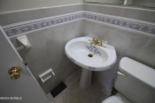 bathroom with tile patterned flooring, tile walls, and toilet