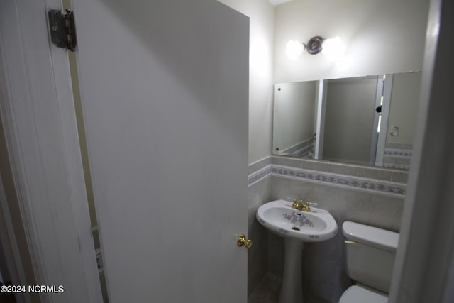 bathroom with toilet, decorative backsplash, and tile walls